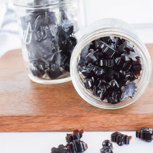 mason jars with elderberry gummies and spilled over to the table top.