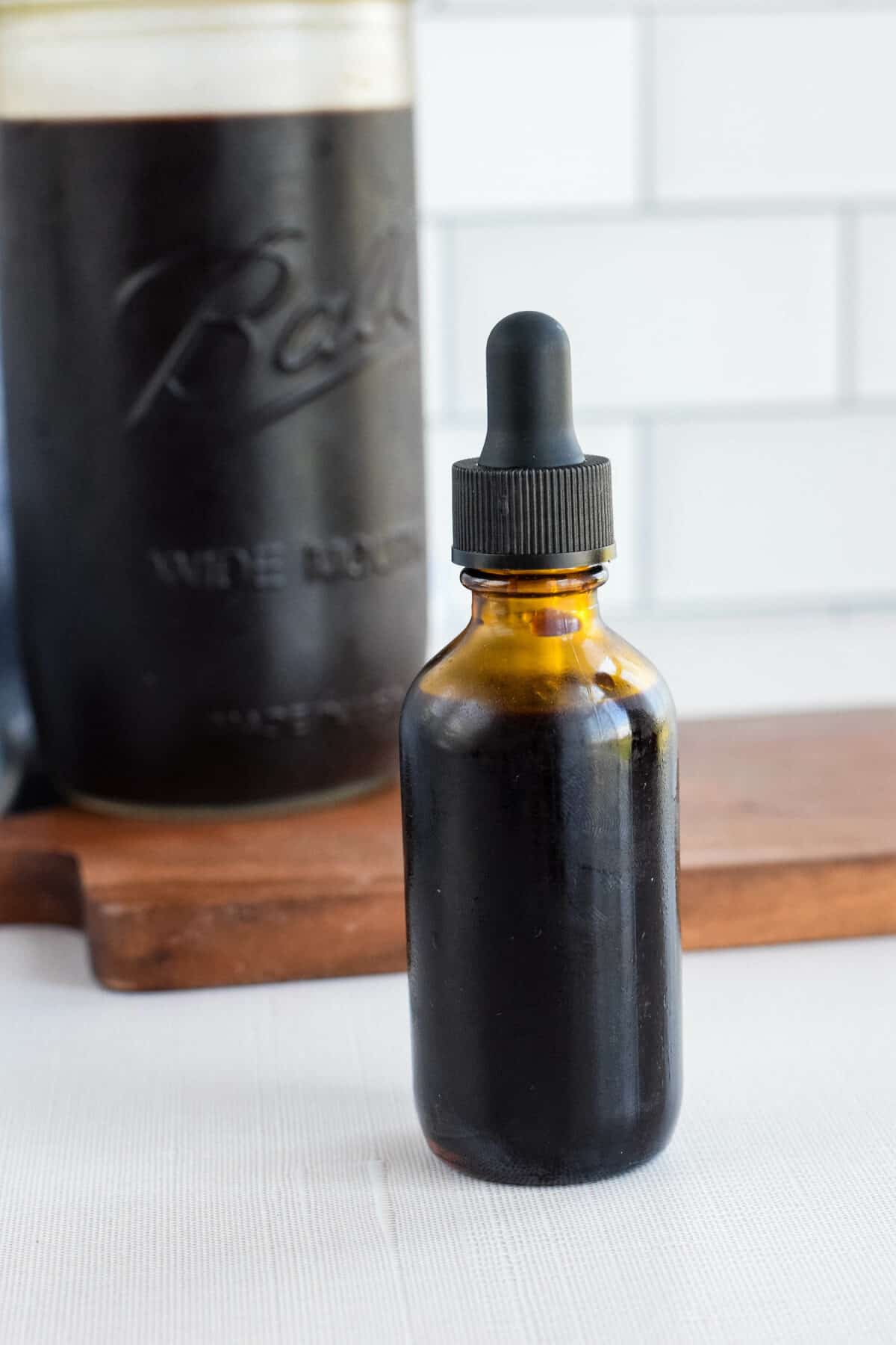 dropper bottle and mason jar with finished elderberry syrup.