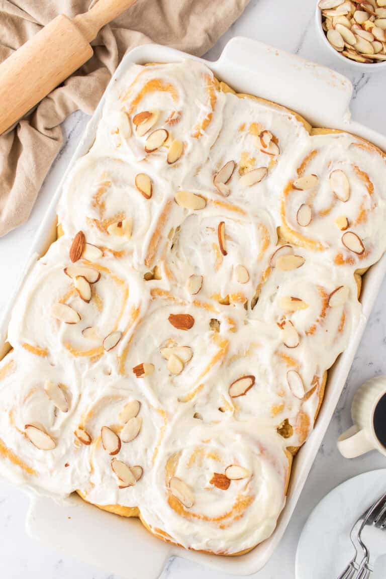 white baking dish with the almond sweet rolls with cream cheese frosting.