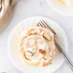 white plate with a slice of the almond sweet rolls with a fork to the side.