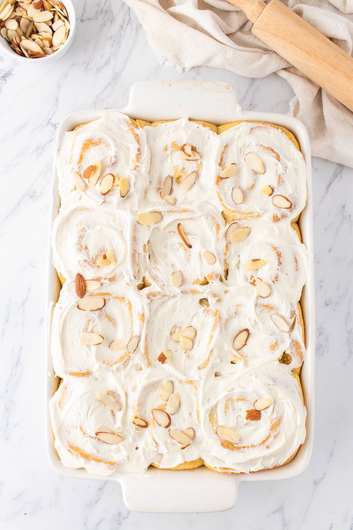 finished almond sweet rolls with cream cheese frosting and almond slices on top.