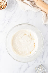 small mixing bowl with cream cheese frosting for the almond sweet rolls.