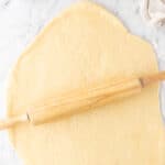 rolling out the sweet dough on a countertop.