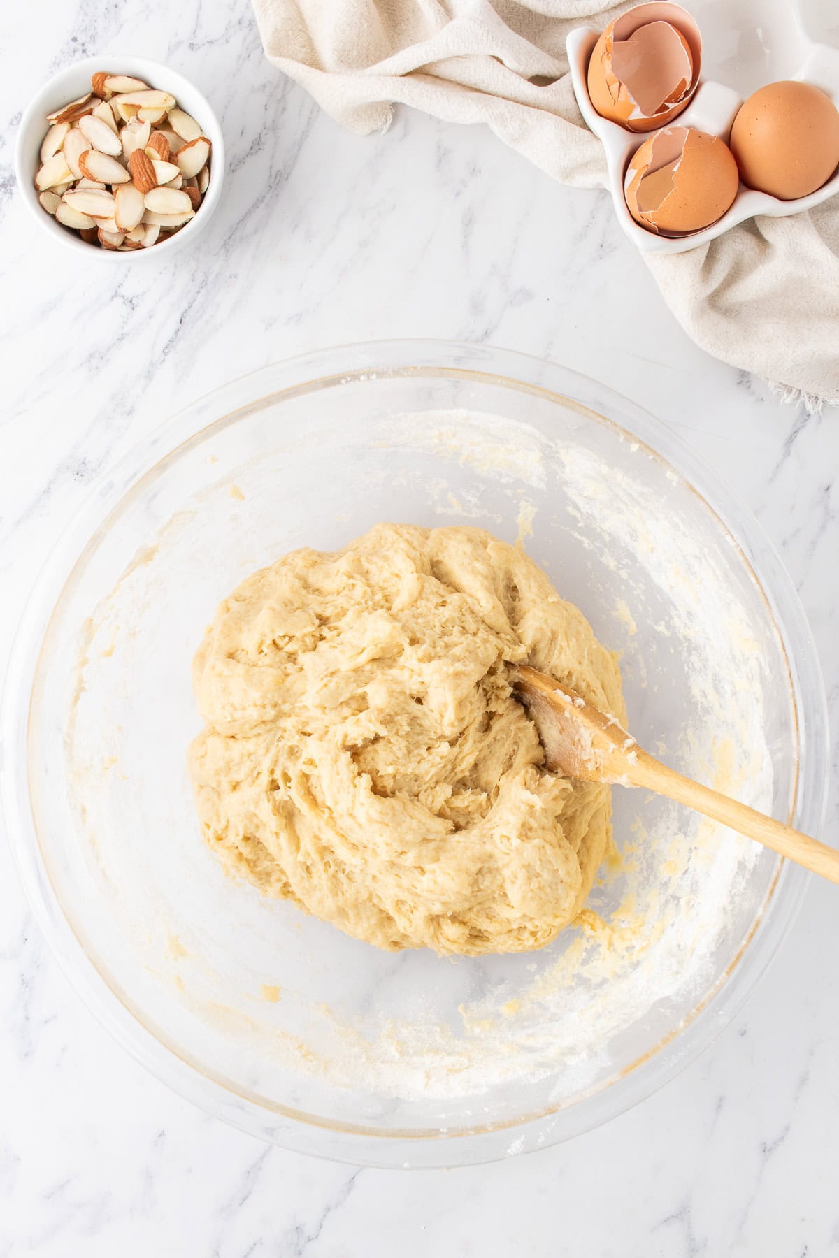 mixing the dough in a large bowl with a wooden spoon. 