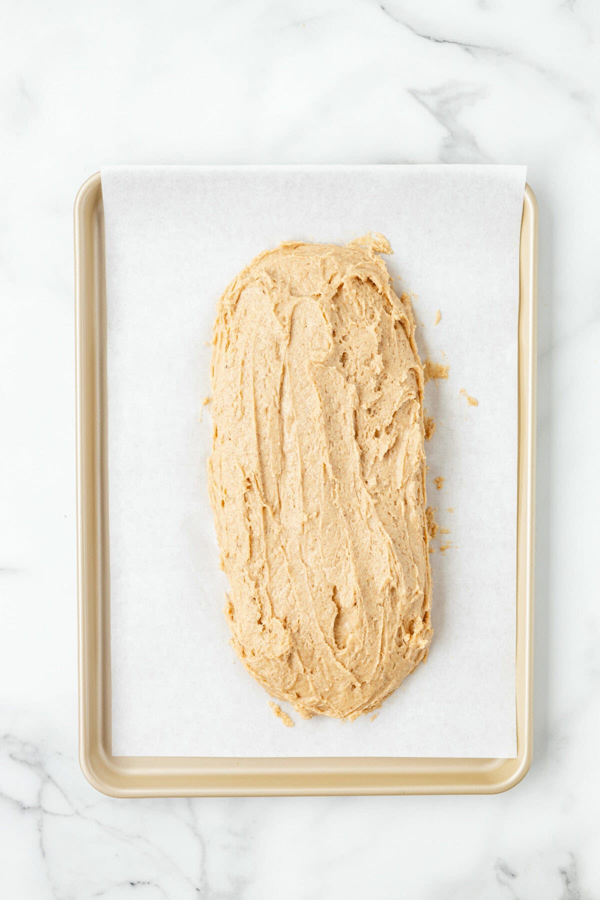 spreading the biscotti dough on the parchment paper lined baking sheet. 