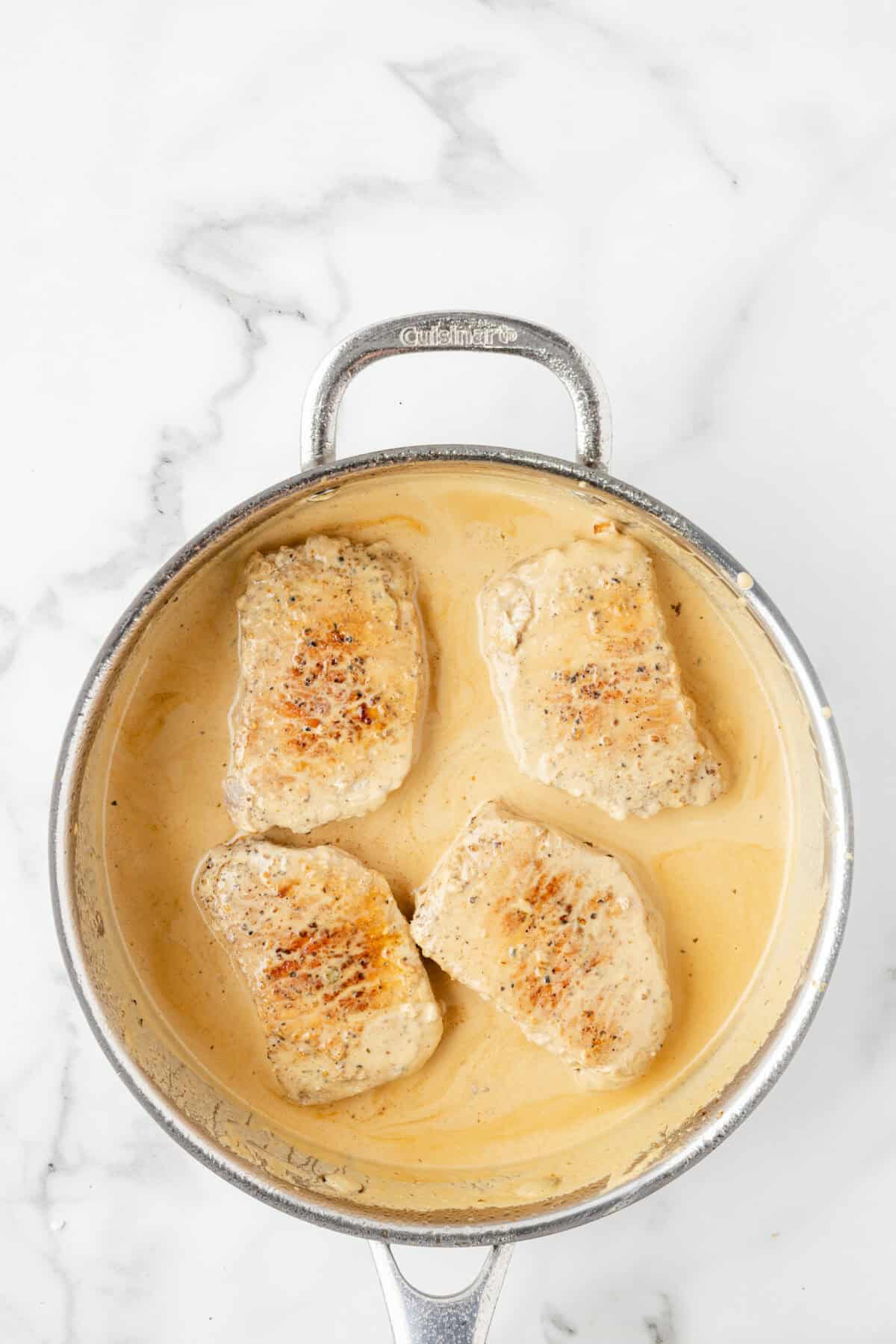 pork chops smothered with cream sauce in the skillet. 