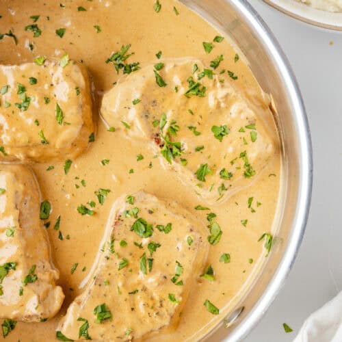 closeup image of creamy pork chops in a skillet.