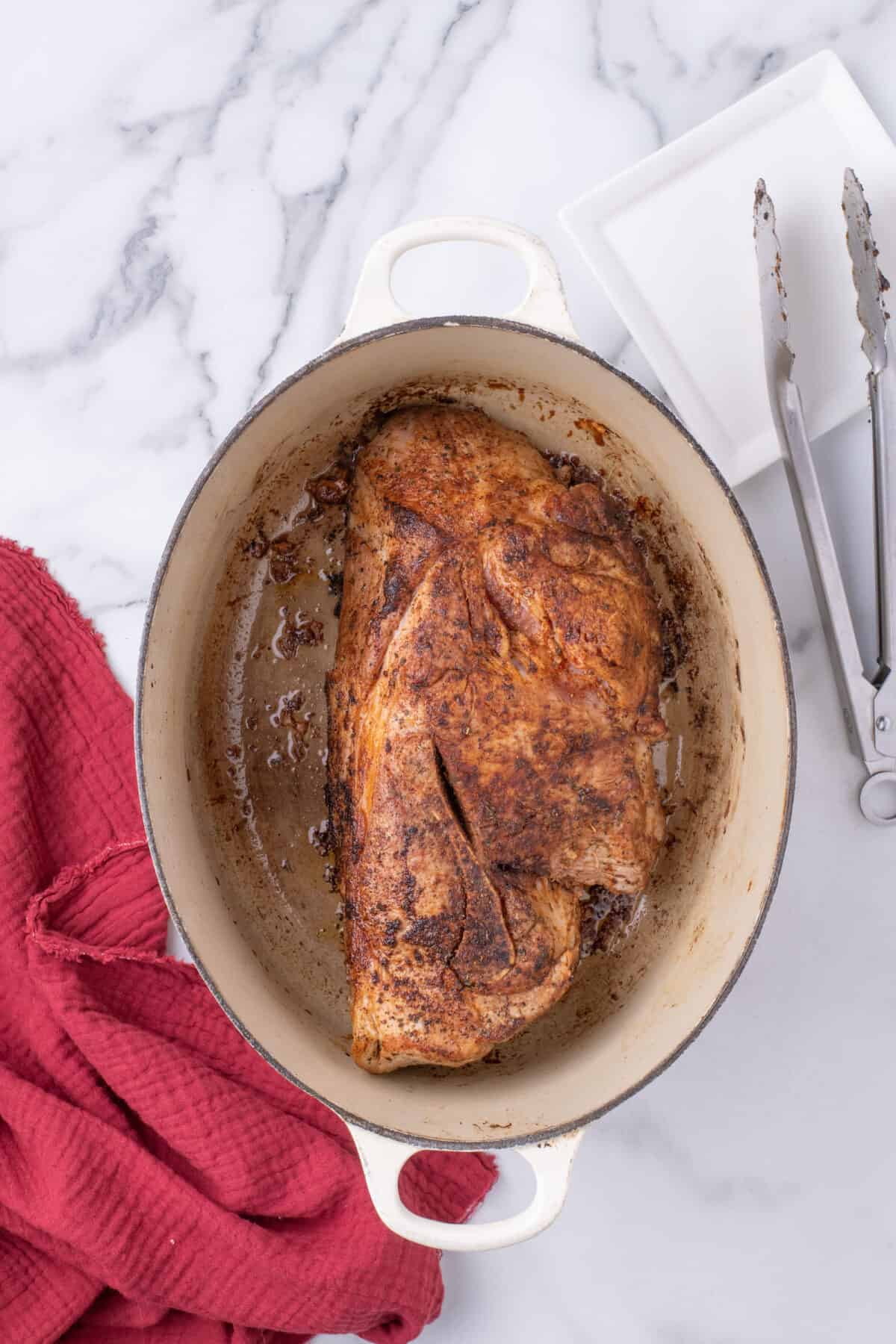 seared pork shoulder in a dutch oven braising pan. 