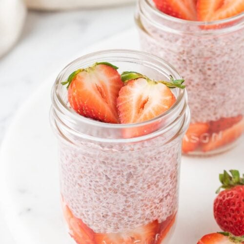 two small mason jars filled with plant based strawberry chia pudding.