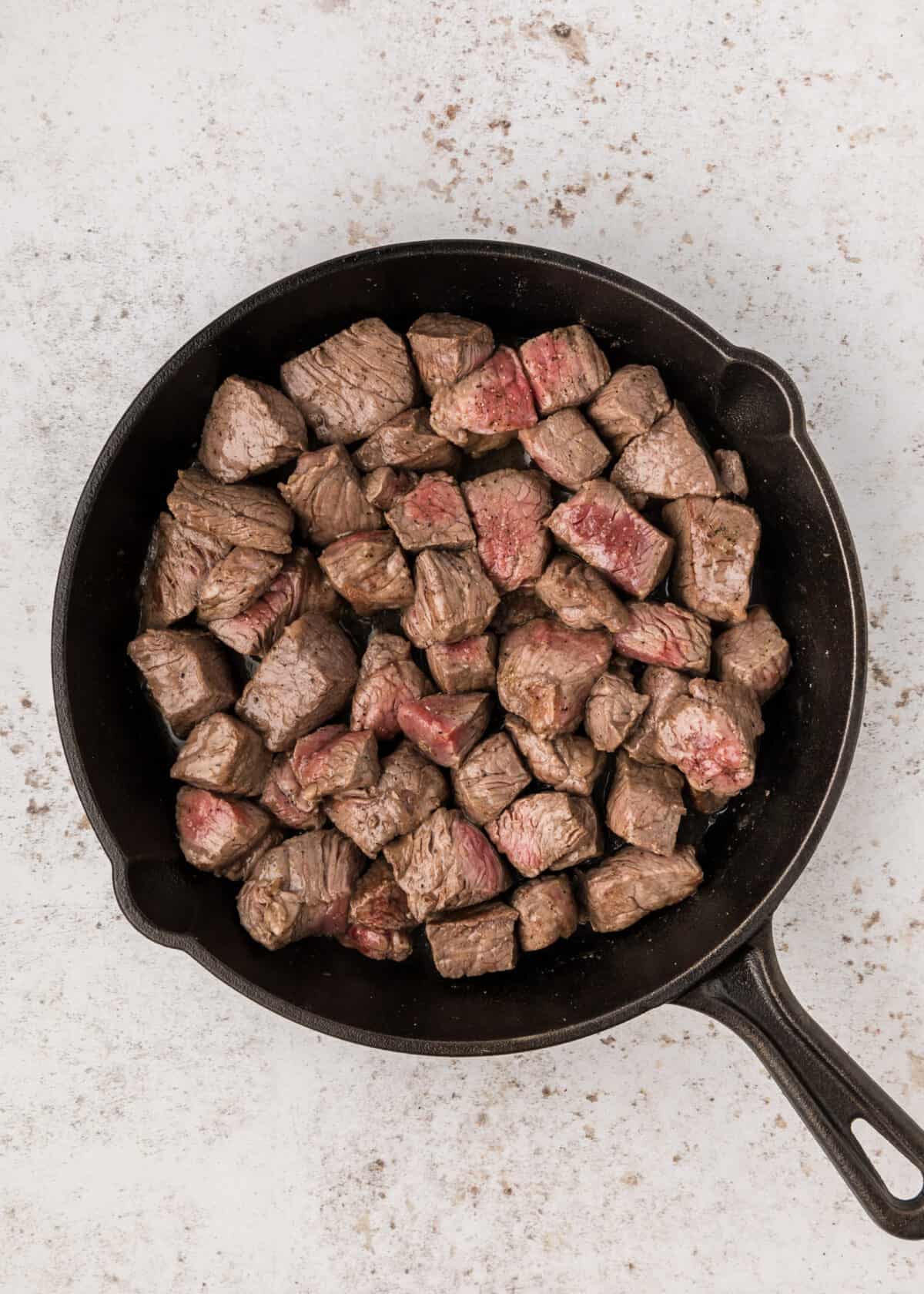 cast iron skillet cooking garlic steak bites. 