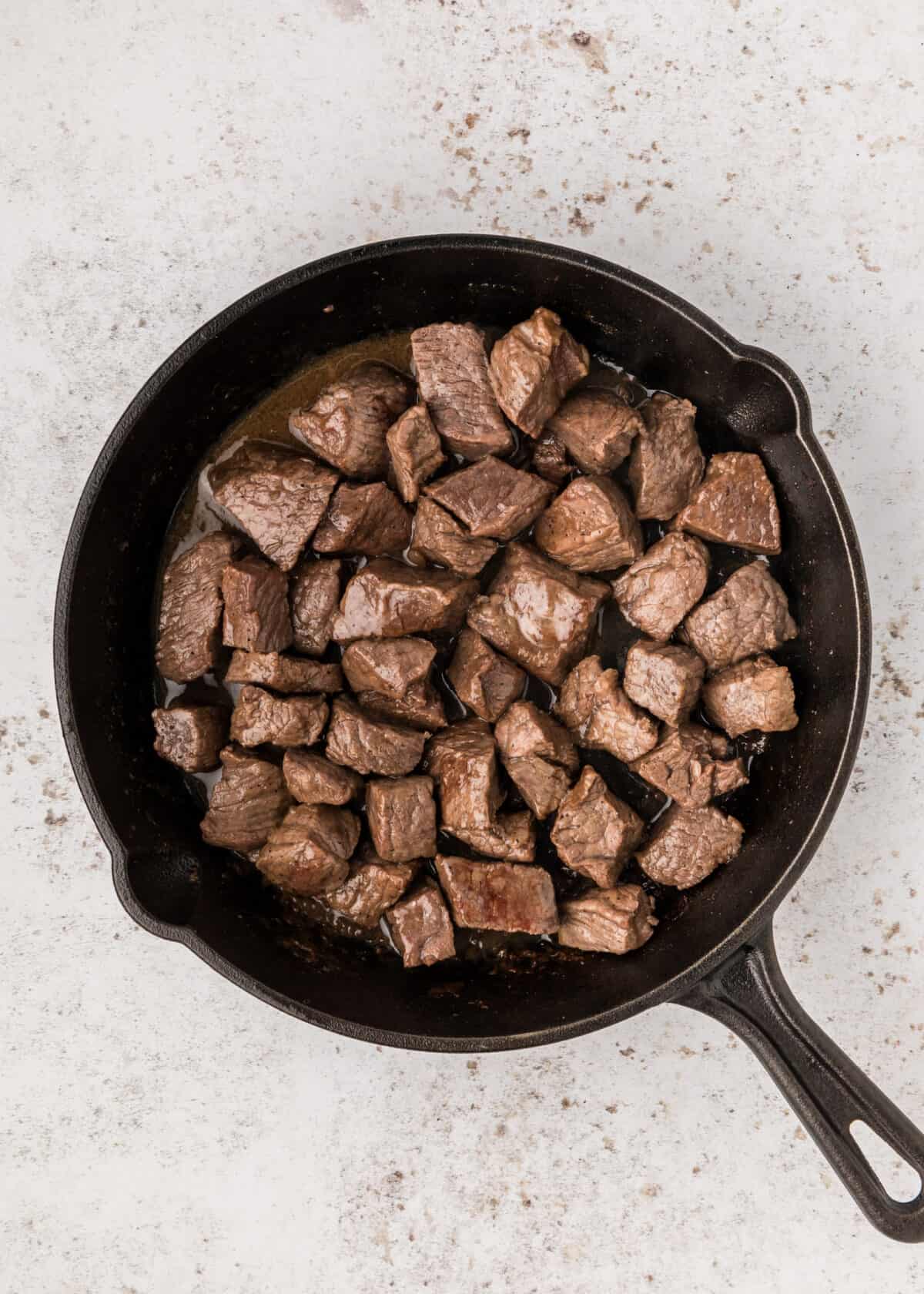 cooking steak bites in a cast iron skillet. 