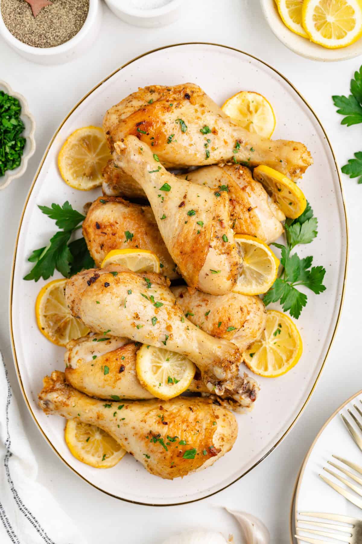 finished baked lemon chicken drumsticks on a white platter. 