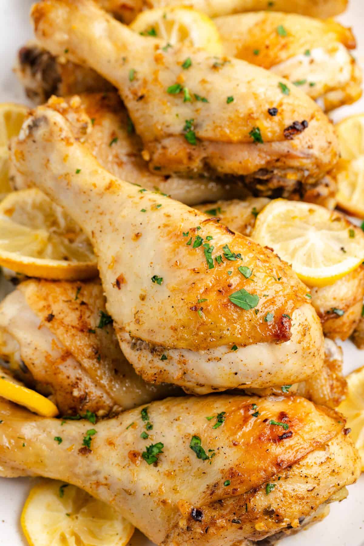 platter with baked lemon chicken drumsticks stacked on top of each other. 