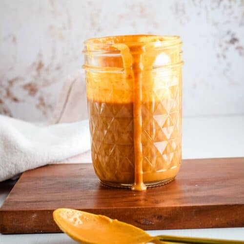 thai peanut sauce in a small mason jar with a spoon resting to the side.