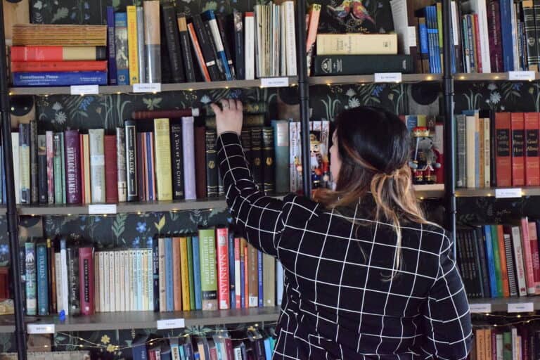 Mary gathering books from the home library bookshelves.