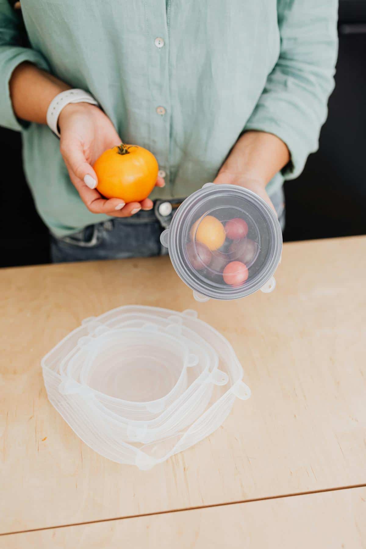 Person holding fresh vegetables and using eco-friendly storage in kitchen.