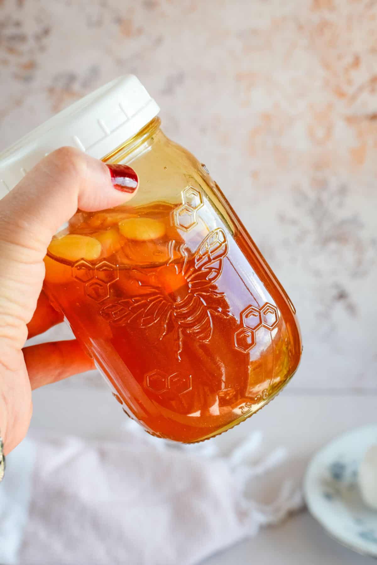 giving the mason jar with the garlic cloves and honey a gentle shake.