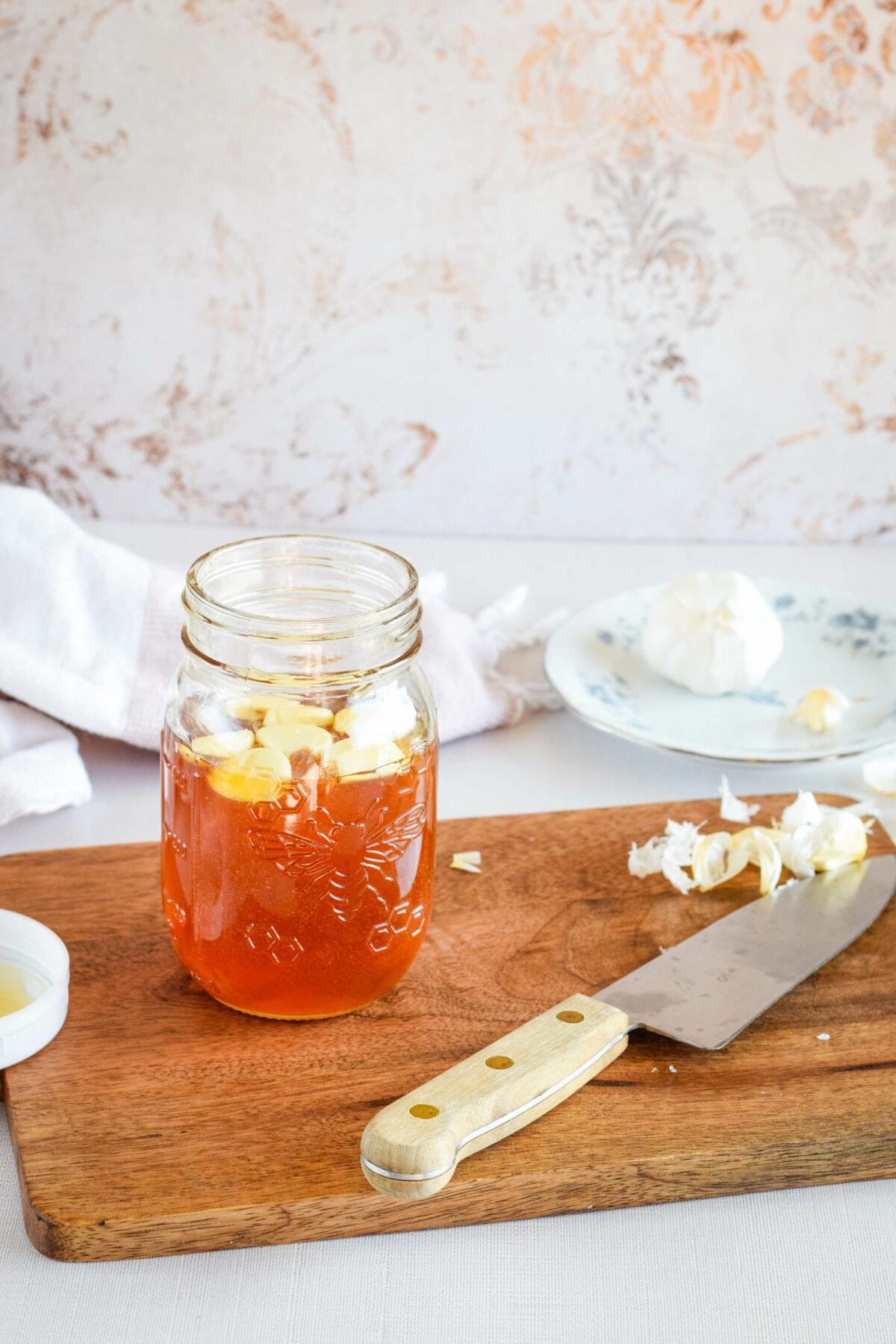 filling a small mason jar with garlic cloves and honey.
