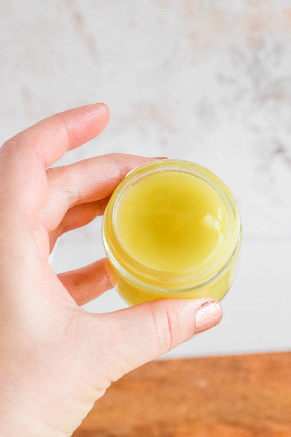 holding a small glass jar of the Homemade Eucalyptus Salve in hand. 