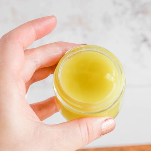 holding a small glass jar of the Homemade Eucalyptus Salve in hand.