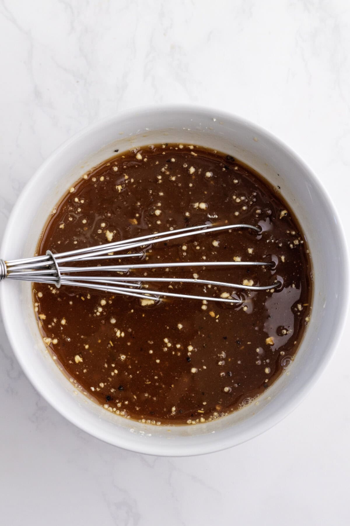 sauce for the slow cooker beef stew in a white bowl with a whisk.