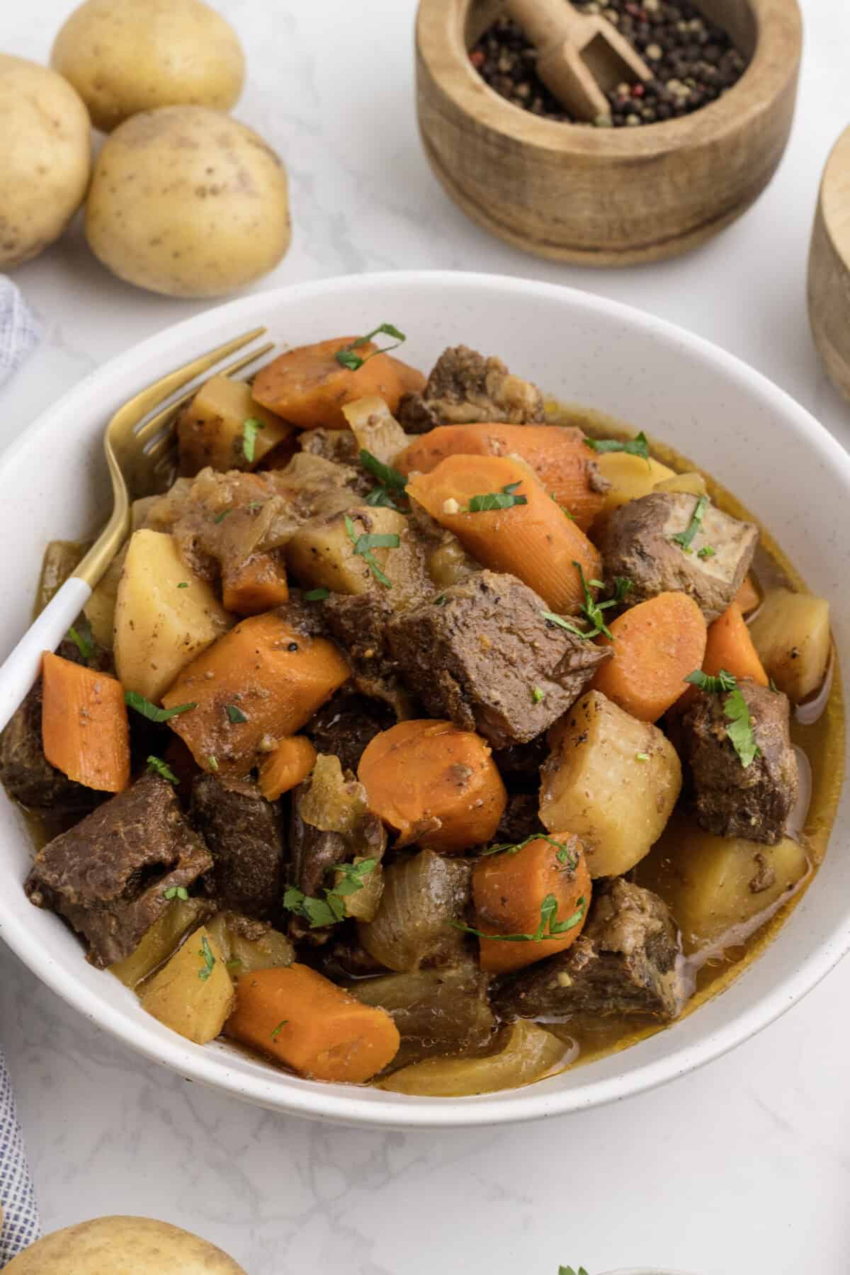 closeup image of the honey balsamic beef stew in a white bowl.