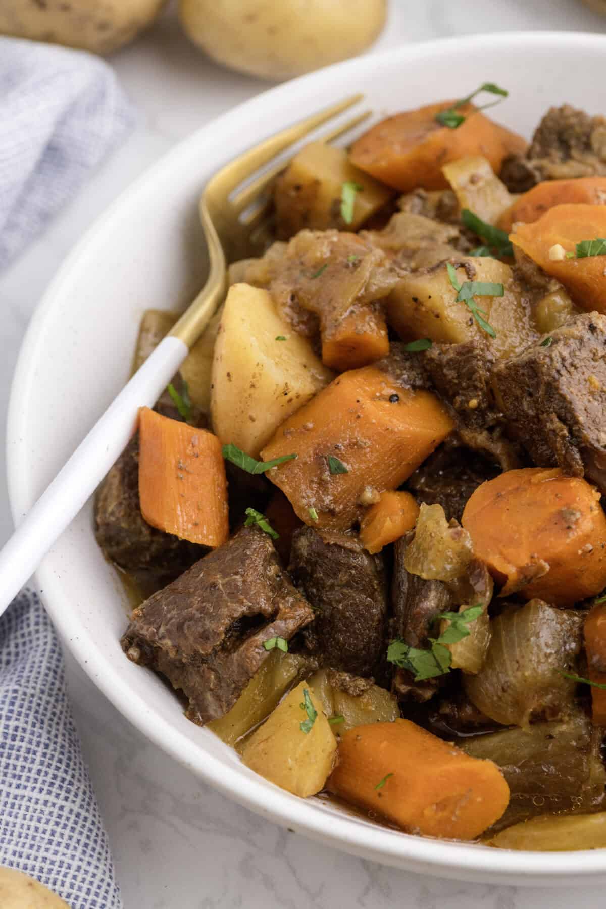 honey balsamic beef stew in a large white bowl with a fork resting to the side.