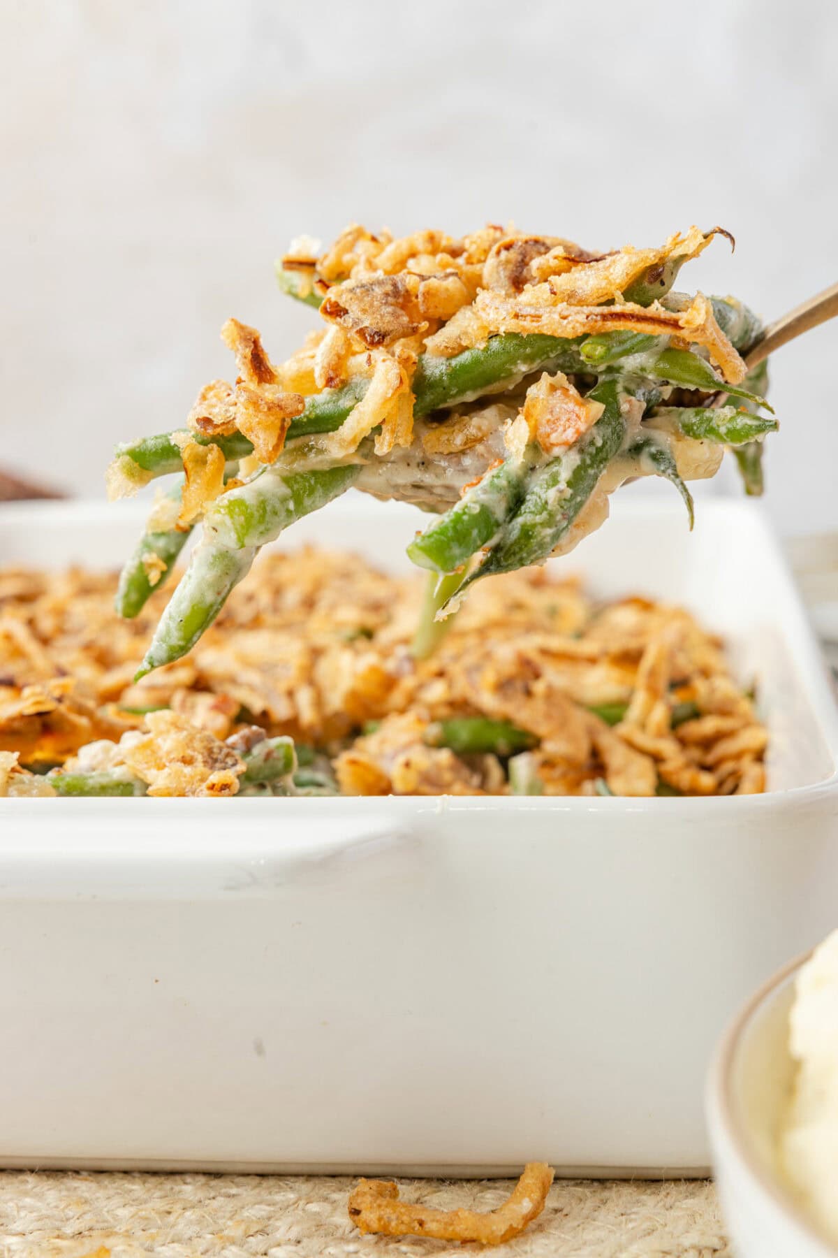 fresh green been casserole on a fork over a white casserole dish to show the texture. 