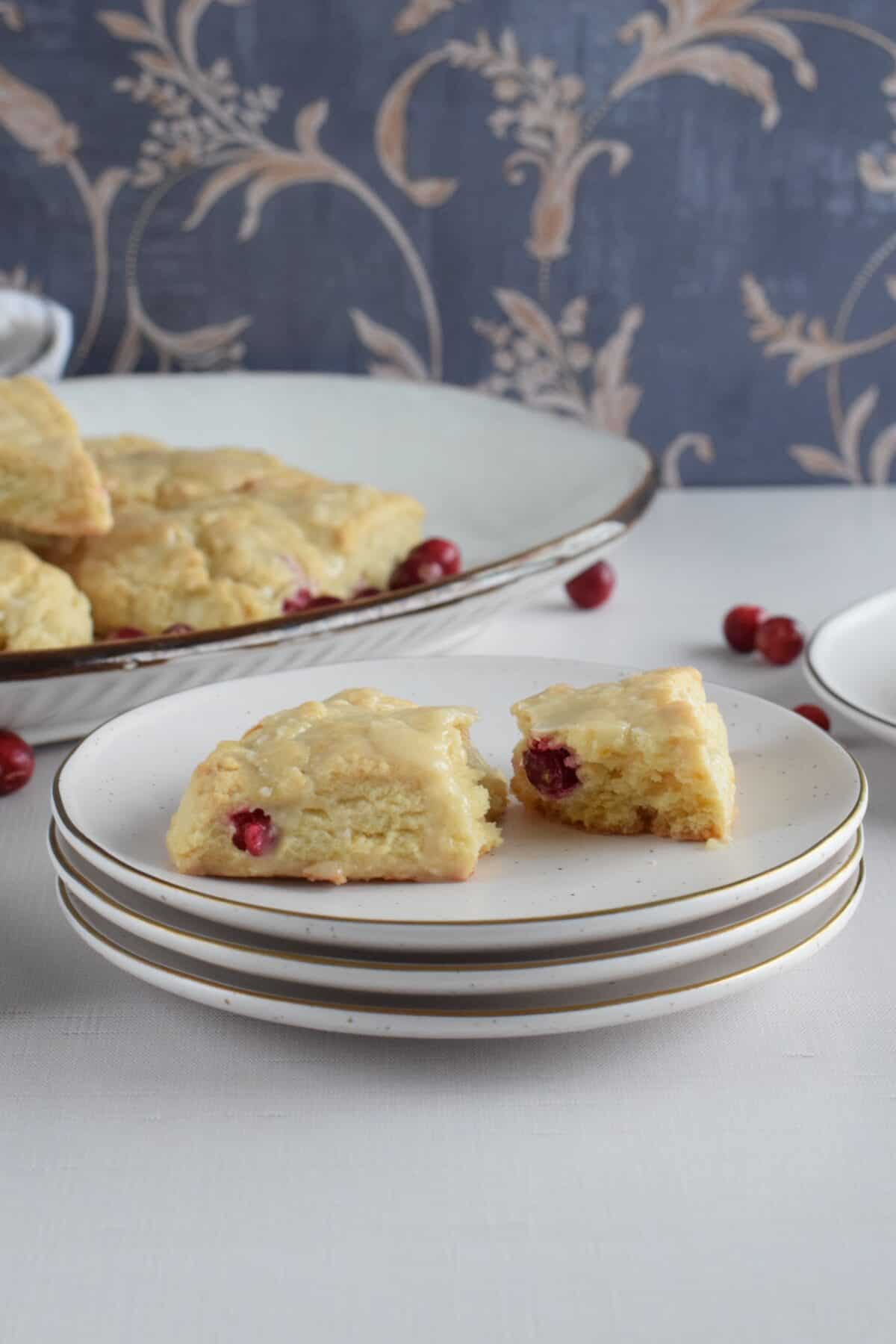 Cranberry orange scone on a stack of plates broken in half to show texture.