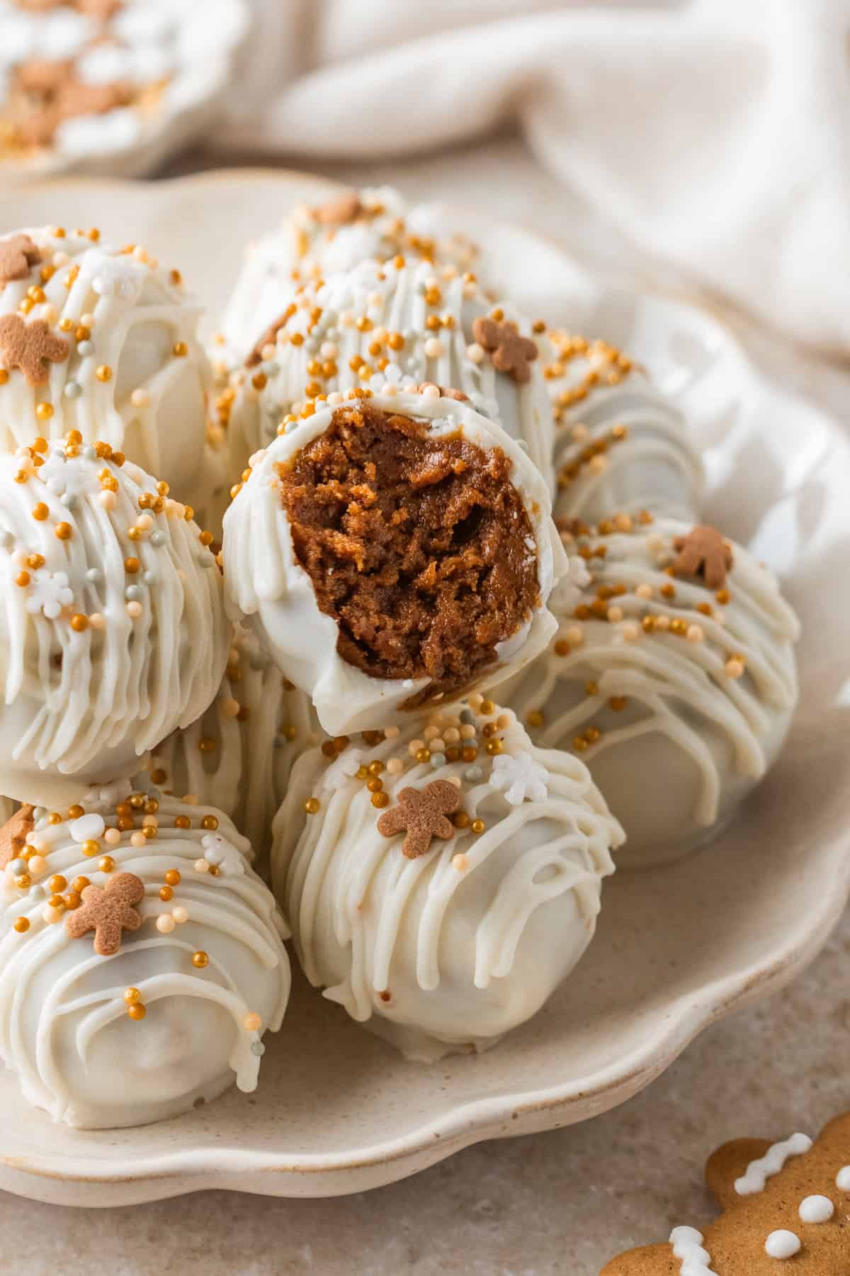 gingerbread truffle with a bite taken out of it on a stack of other truffles on a plate.
