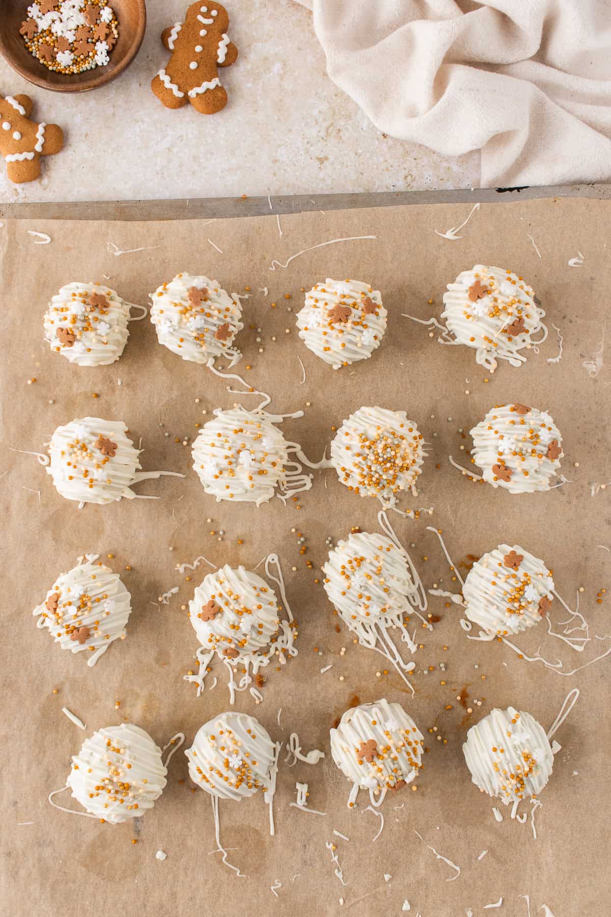 gingerbread truffles on a parchment paper lined cookie sheet and drizzled with white chocolate.