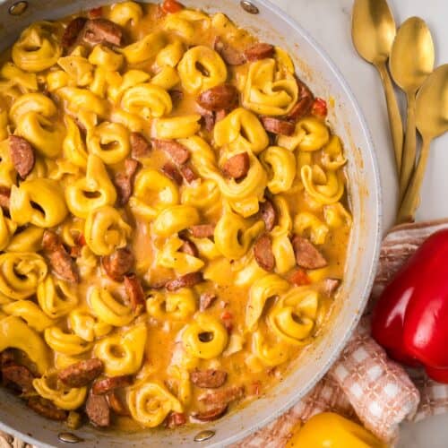 skillet with finished creamy cajun tortellini resting on a counter.