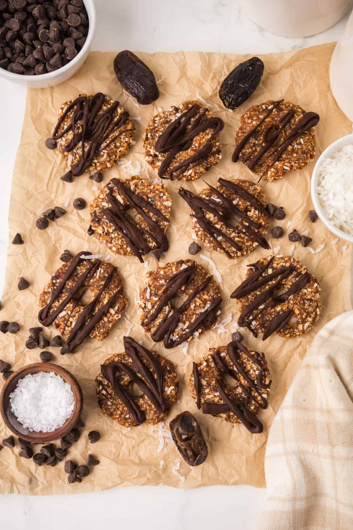 sheet of parchment paper with finished date Samoas, topped with chocolate drizzle and sprinkle of sea salt.