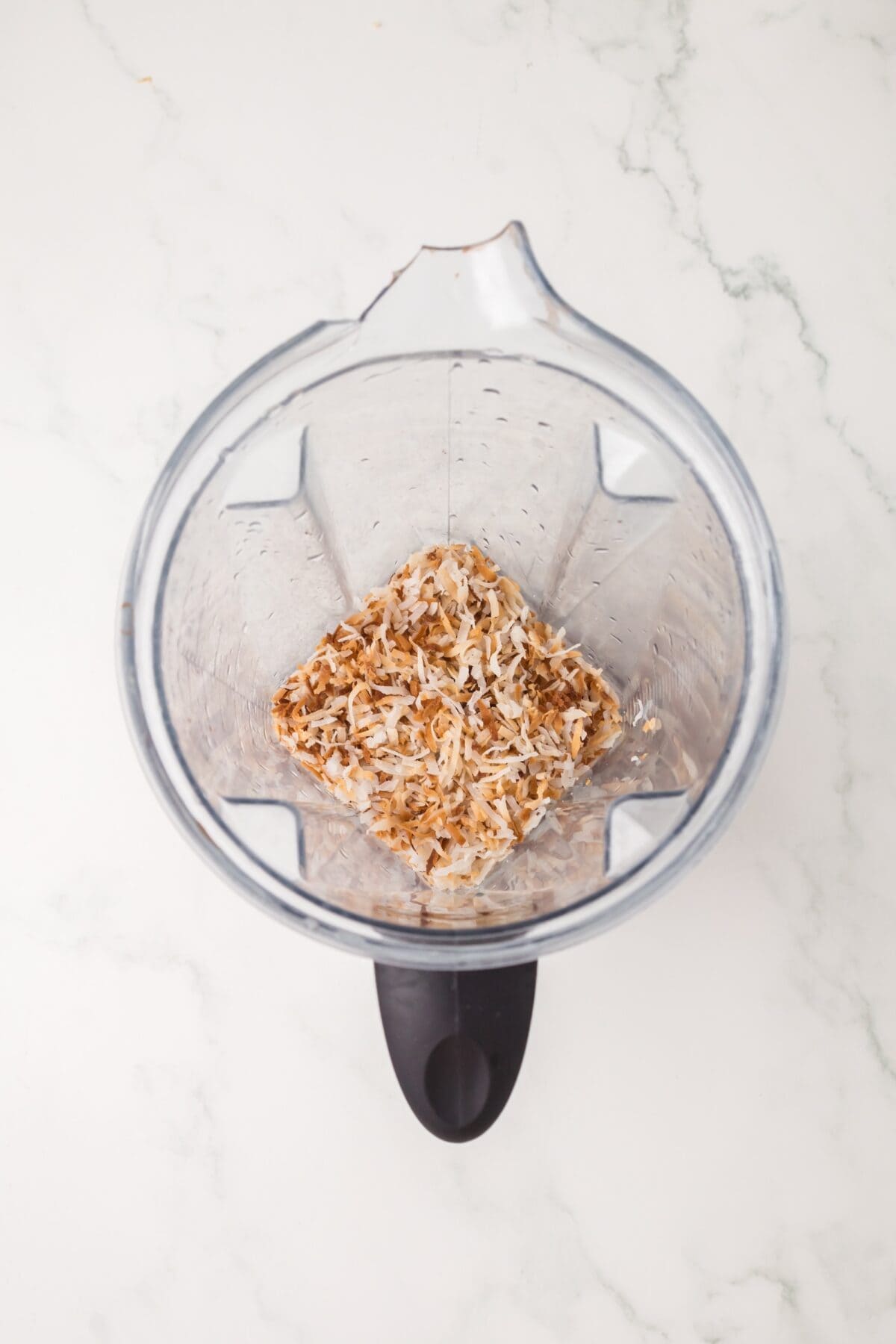 adding the toasted coconuts to a food processor.
