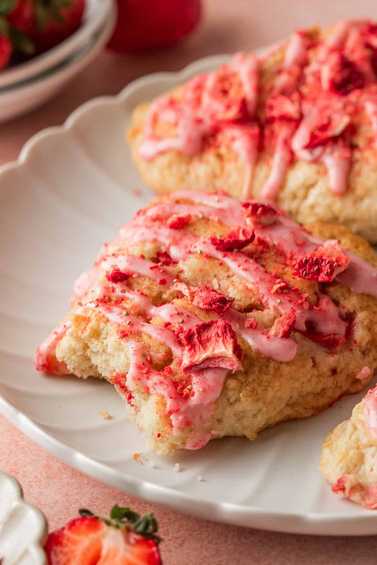 strawberry scones on a white plate with one bite taken out of it. 