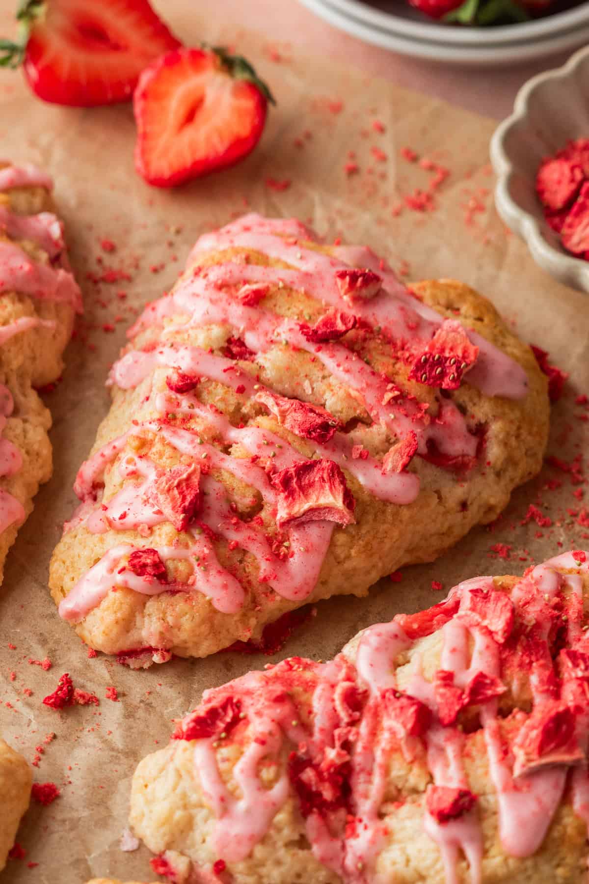 strawberry scones with strawberry glaze resting on parchment paper.
